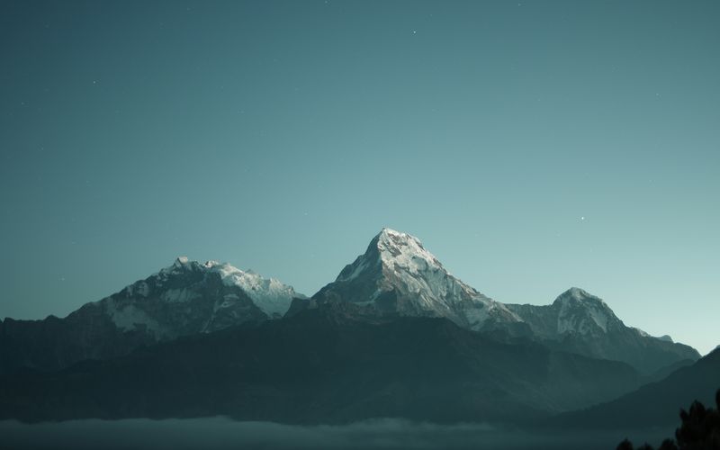 A single snow-capped mountain peak against a clear teal sky