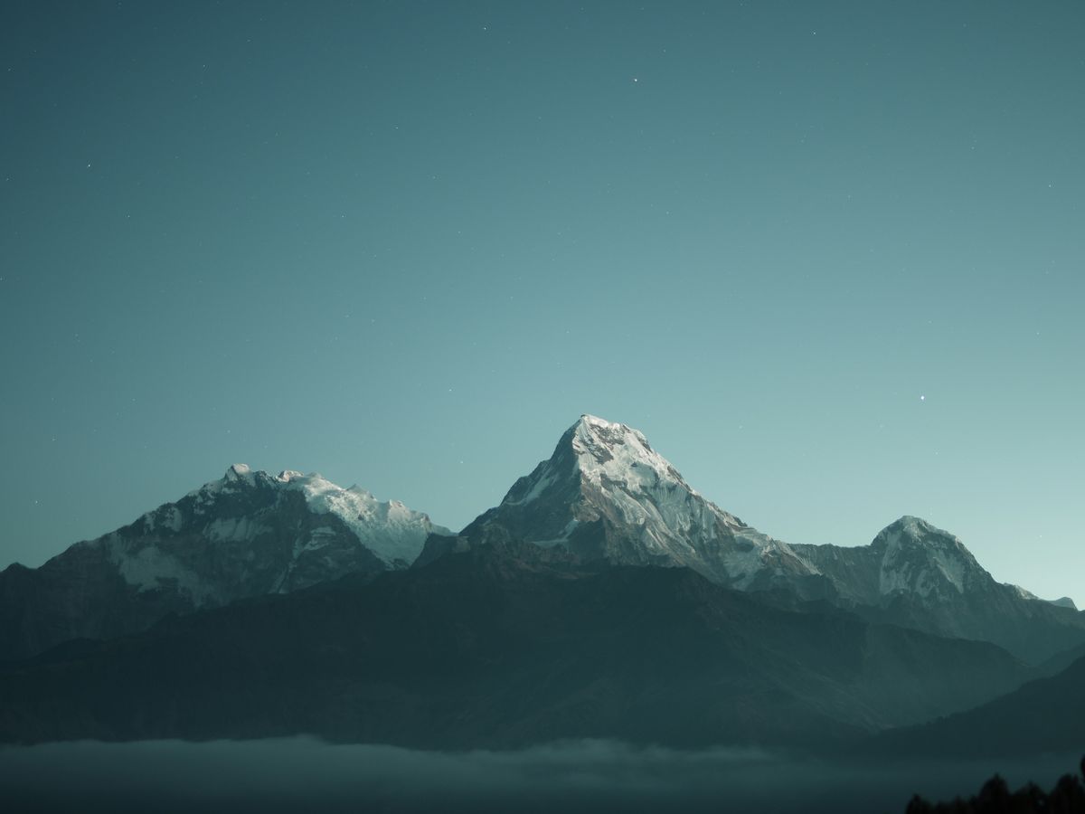 A single snow-capped mountain peak against a clear teal sky